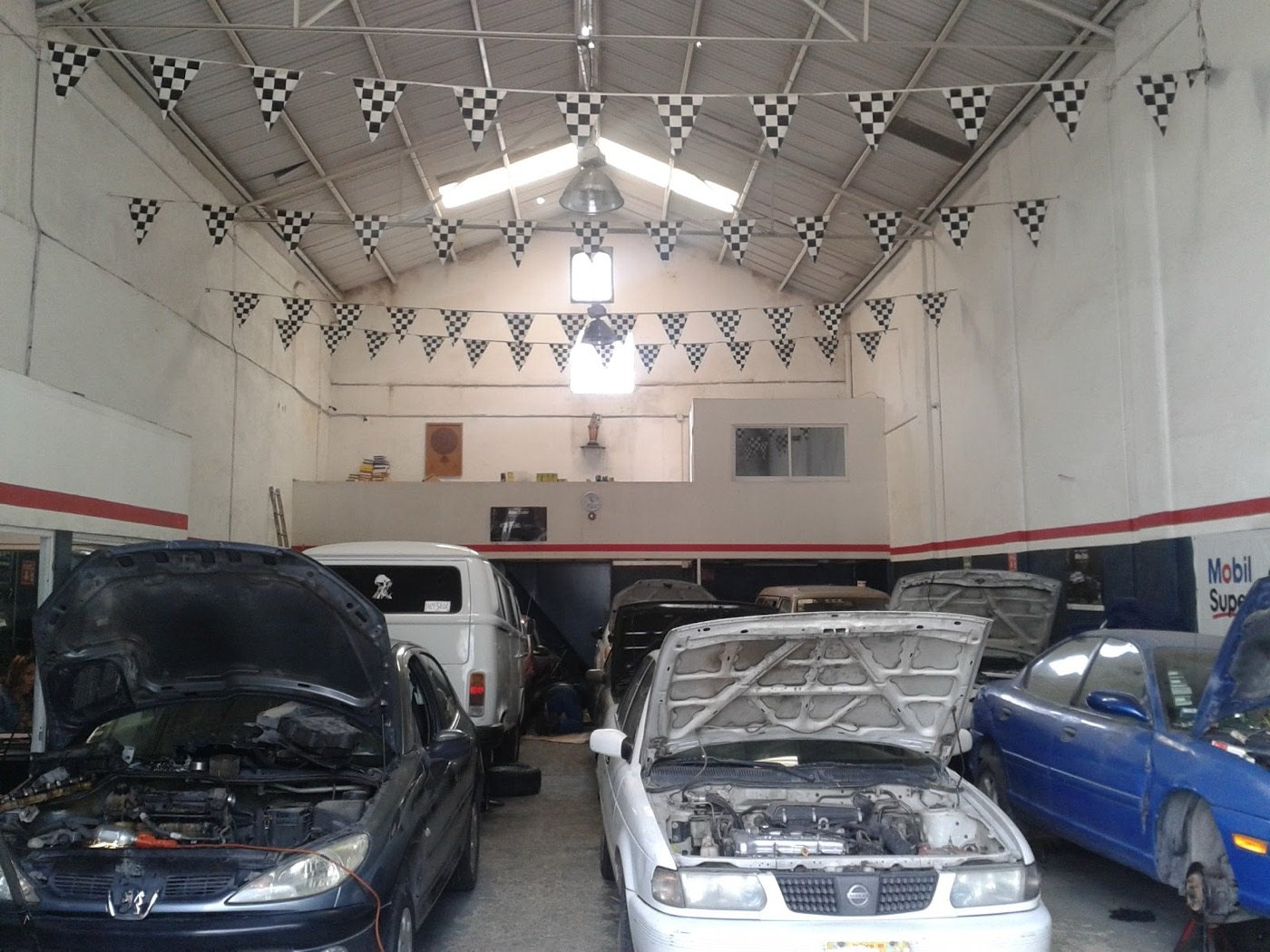 Nave del taller con banderines a cuadros y autos en servicio